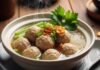 Resep Bakso Ayam Kenyal Gurih – Gampang & Enak! Sup bakso hangat disajikan dengan mie, irisan daun bawang, dan taburan bawang goreng, menciptakan pengalaman kuliner yang menggoda.