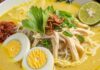 Resep Soto Ayam Kuah Santan Gurih Ala Rumahan yang Bikin Nagih Makanan lezat ini adalah semangkuk soto ayam kuah kuning, disajikan dengan telur, mi, dan taburan daun hijau segar.